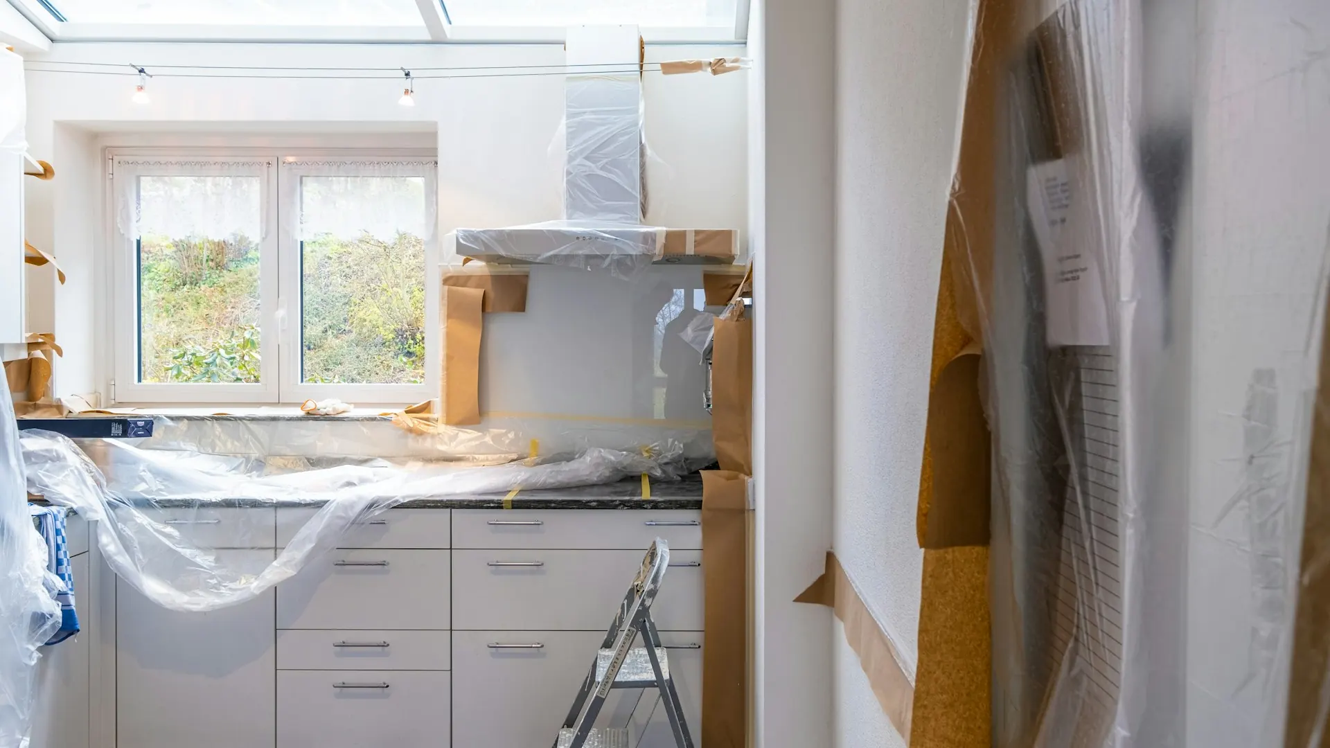 Kitchen under repair with cabinets covered in plastic sheeting